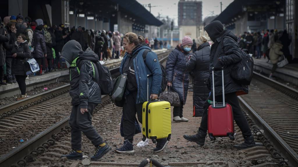 Menschen überqueren die Gleise im Hauptbahnhof Kiews, um aus der Ukraine zu fliehen.