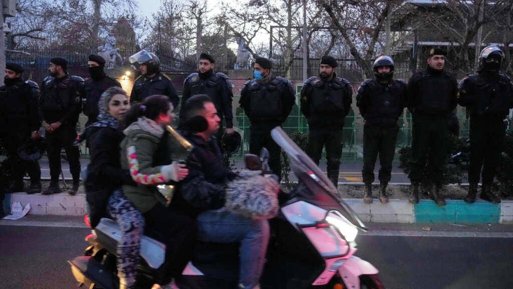 Polizisten schützen die britische Botschaft während einer Demonstration von Hardliner-Anhängern der iranischen Regierung, während Menschen auf ihrem Motorrad an den Einsatzkräften vorbei fahren. Foto: Vahid Salemi/AP/dpa