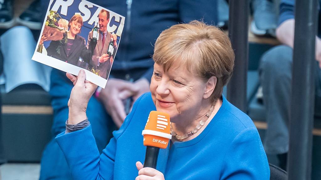 Die frühere Bundeskanzlerin Angela Merkel ist zu Gast in der Live-Radioshow «Studio 9», des Deutschlandfunks im Humboldt Forum und schaut ein altes Foto mit ihr und Friedrich Merz an. Foto: Michael Kappeler/dpa