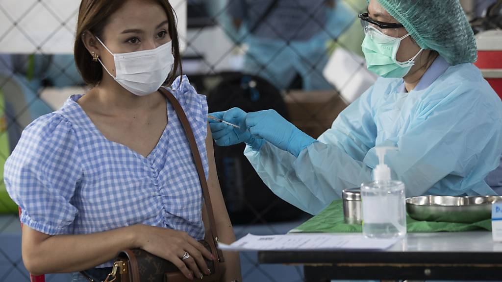 Eine Gesundheitsmitarbeiterin impft eine Frau in Bangkok, die in einer Vergnügungsstätte arbeitet. Foto: Sakchai Lalit/AP/dpa