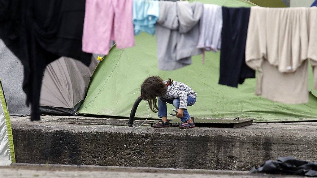 Ein Mädchen trinkt in einem griechischen Flüchtlingslager bei Idomeni Wasser aus einem Schlauch: Die EU-Kommission hat am Mittwoch einen Fairness-Mechanismus zur Verteilung von Flüchtlingen vorgeschlagen, um Länder wie Griechenland zu entlasten (Archiv).