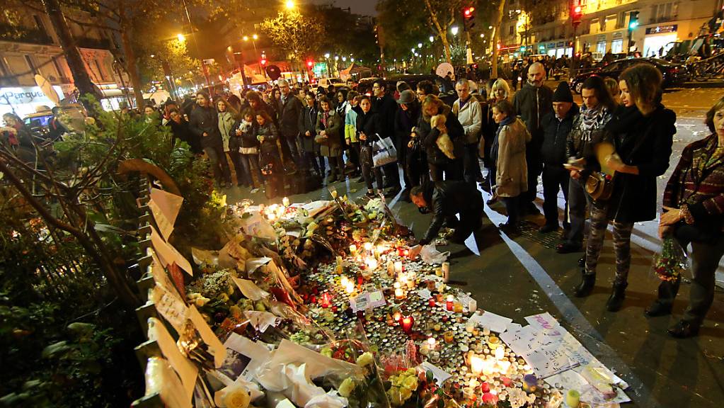 ARCHIV - Trauernde Menschen zünden am 16.11.2015 vor dem Bataclan Theater in Paris (Frankreich) Kerzen an und legen Blumen nieder. Bei einer Serie von Terroranschlägen in Paris in der Nacht vom 13. auf den 14. November 2015 wurden mehr als 130 Menschen getötet. Foto: picture alliance / dpa