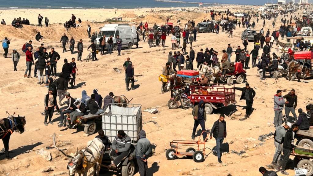 Palästinenser warten an einem Strand auf humanitäre Hilfen. Symbolbild Foto: Mahmoud Essa/AP/dpa