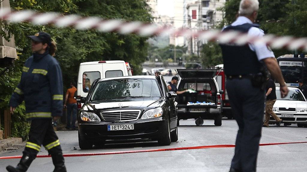 Rettungsdienste am Anschlagsort. Der frühere griechische Ministerpräsident Papademos wurde in seinem Auto durch eine Briefbombe verletzt. Er soll ausser Lebensgefahr sein.