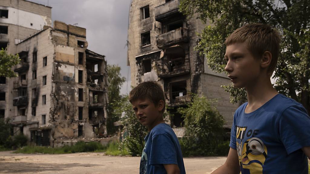 Zwei Jungs gehen in Borodjanka an Wohnhäusern vorbei, die bei Angriffen beschädigt wurden. Foto: Jae C. Hong/AP/dpa