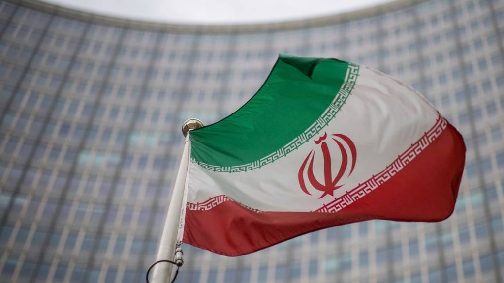 ARCHIV - Eine iranische Nationalflagge weht vor dem Gebäude der Internationalen Atomenergiebehörde (IAEA). Foto: Michael Gruber/AP/dpa