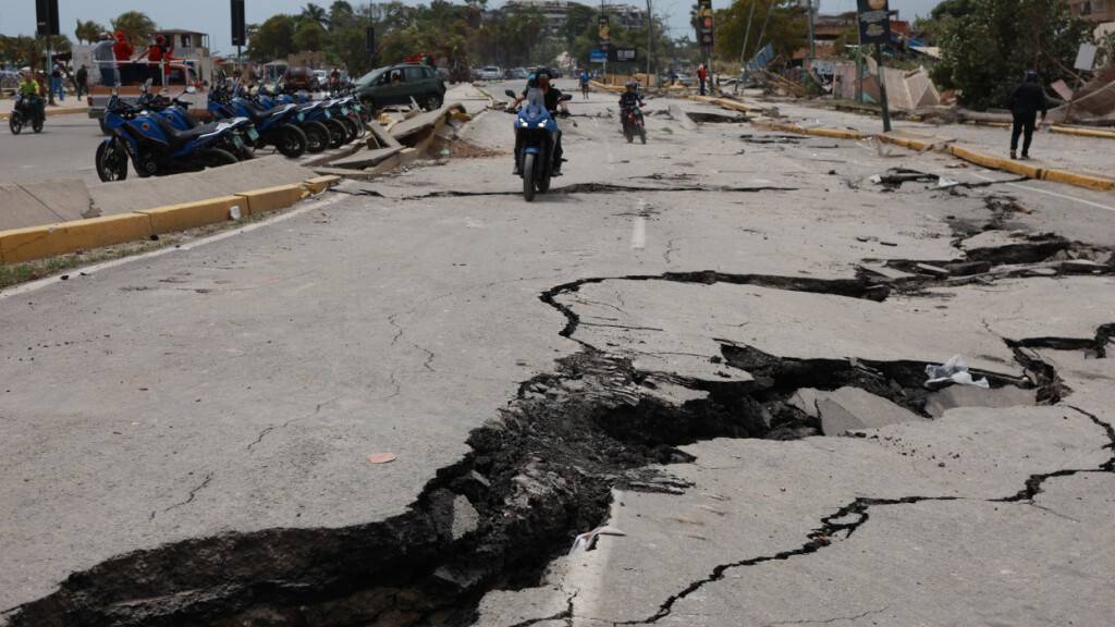 Motorradfahrer fahren auf einer Straße, die durch die Erdbeben, die La Guaira in Venezuela einen Tag zuvor erschüttert hatten, aufgerissen wurde. Foto: Javier Campos/AP/dpa