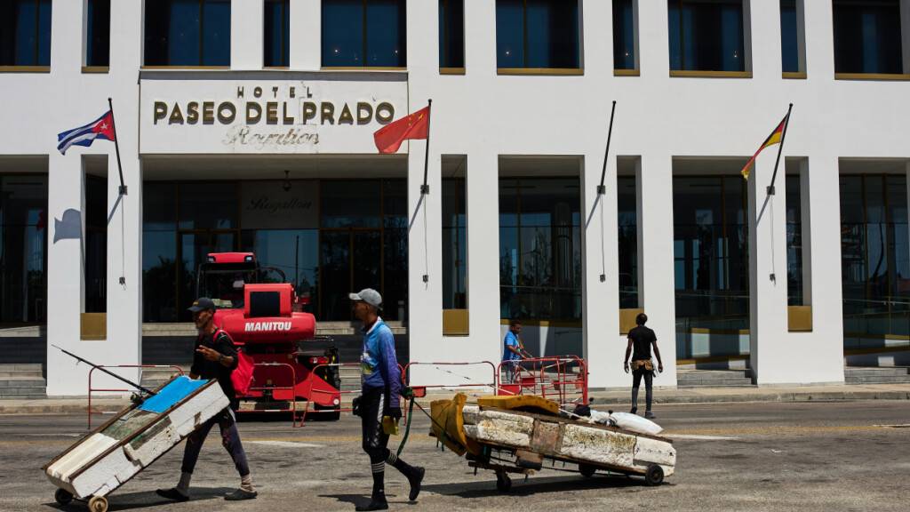 Fischer mit behelfsmäßigen Flößen gehen am Hotel Paseo del Prado der kanadischen Kette Royalton vorbei. Foto: Ramon Espinosa/AP/dpa