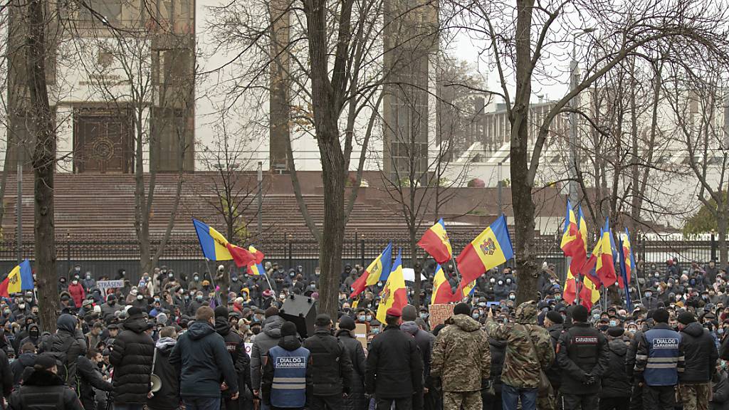 Demonstranten schwenken Fahnen und versammeln sich zu einem Protest zur Unterstützung der gewählten Präsidentin Sandu vor dem Parlamentsgebäude. Tausende Protestierende sind in der Republik Moldau für ihre gewählte Präsidentin Sandu auf die Straße gegangen. Foto: Roveliu Buga/AP/dpa