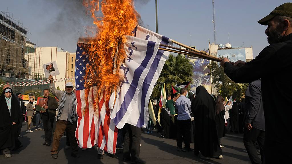 Iranische Demonstranten verbrennen israelische und US-amerikanische Fahnen bei einer anti-israelischen Versammlung in Teheran. Foto: Vahid Salemi/AP/dpa