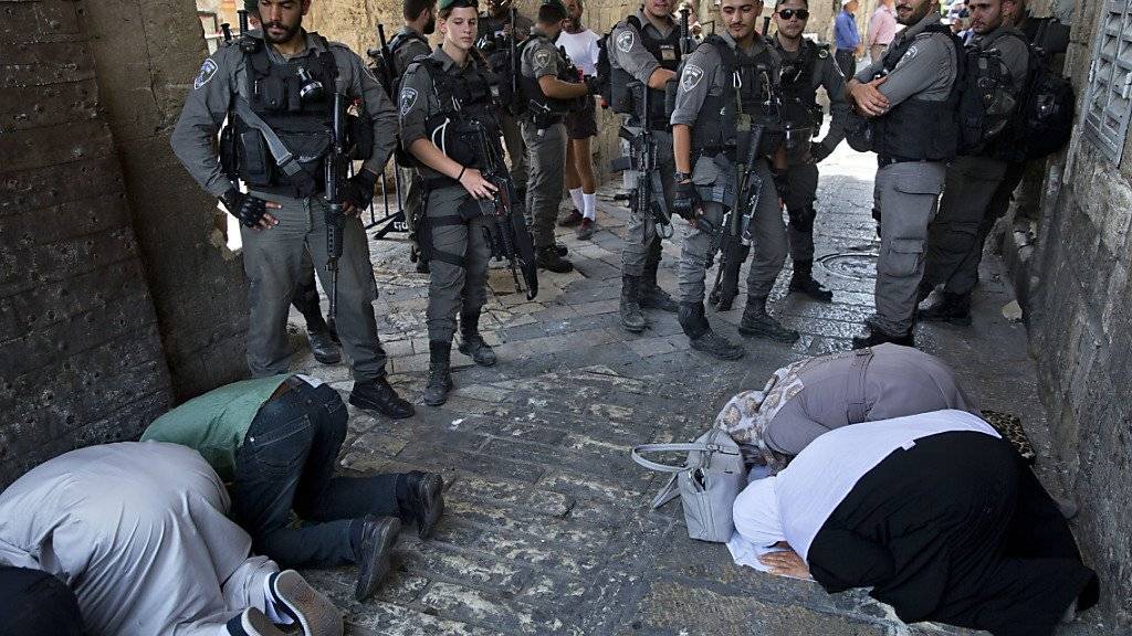 Muslimische Gläubige beten in der Jerusalemer Altstadt, beobachtet von israelischen Grenzpolizisten.