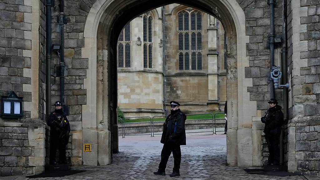 Polizisten bewachen das Tor von Schloss Windsor. Ein bewaffneter Mann hat sich kurzfristig Zugang zu Schloss Windsor verschafft, konnte aber festgenommen werden. Die Thames Valley Police berichtete am Samstag, dass der 19-Jährige gegen 8.30 Uhr die Sicherheitszone durchbrochen hatte. Foto: Alastair Grant/AP/dpa