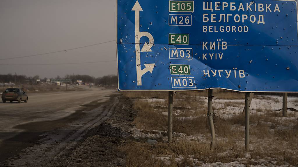 ARCHIV - Ein Auto fährt an einem von Kugeln und Granatsplittern beschädigten Straßenschild auf der Straße zur russischen Stadt Belgorod vorbei. Foto: Vadim Ghirda/AP/dpa