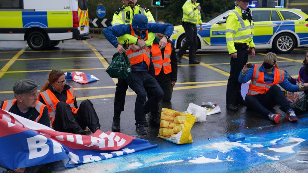 Polizisten nehmen Aktivisten der Organisation «Insulate Britain» auf einer Londoner Autobahn fest. Foto: Steve Parsons/PA Wire/dpa