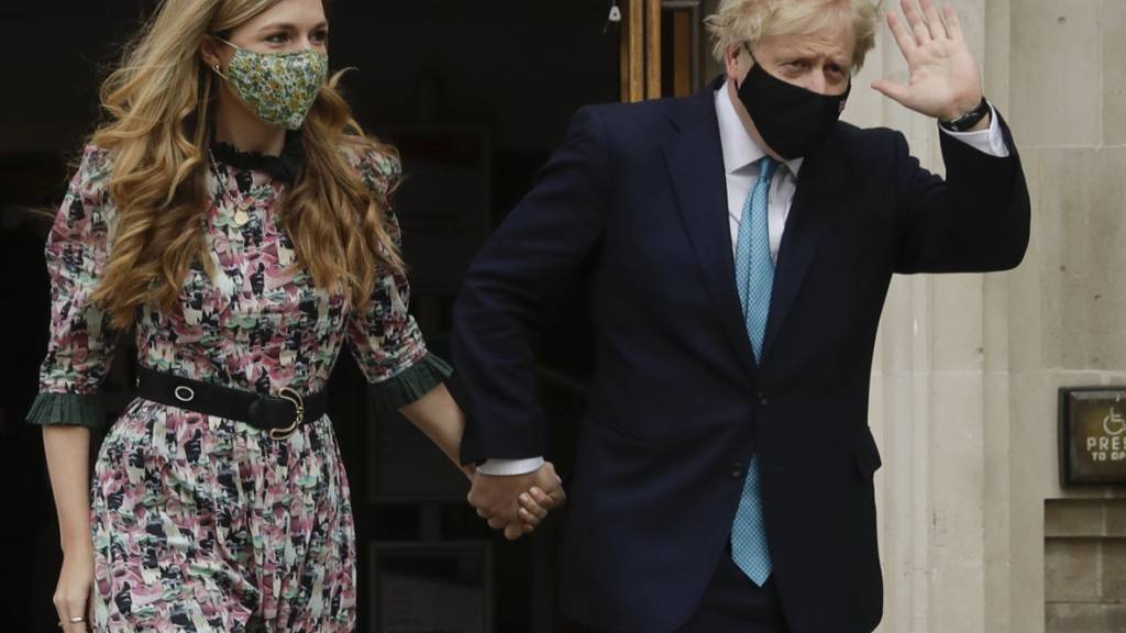 dpatopbilder - Boris Johnson (r), Premierminister von Großbritannien, winkt, als er mit seiner Verlobten Carrie Symonds nach ihrer Stimmenabgabe das Methodist Central Hall verlässt. Foto: Matt Dunham/AP/dpa