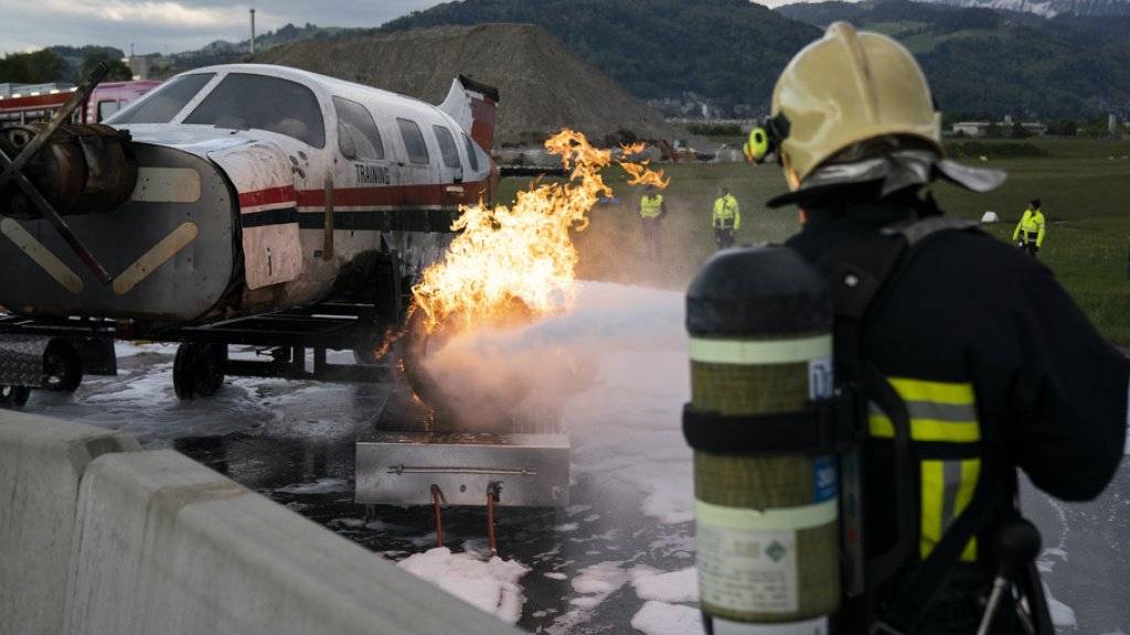 Ein Kleinflugzeug brennt, ein Feuerwehrmann greift ein: Notfallübung auf dem Flugplatz in Thun.