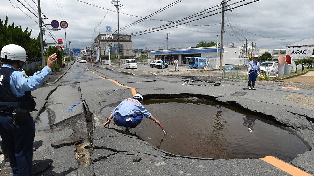 Arbeiter checken die Schäden durch ein Erdbeben an einer Strasse.
