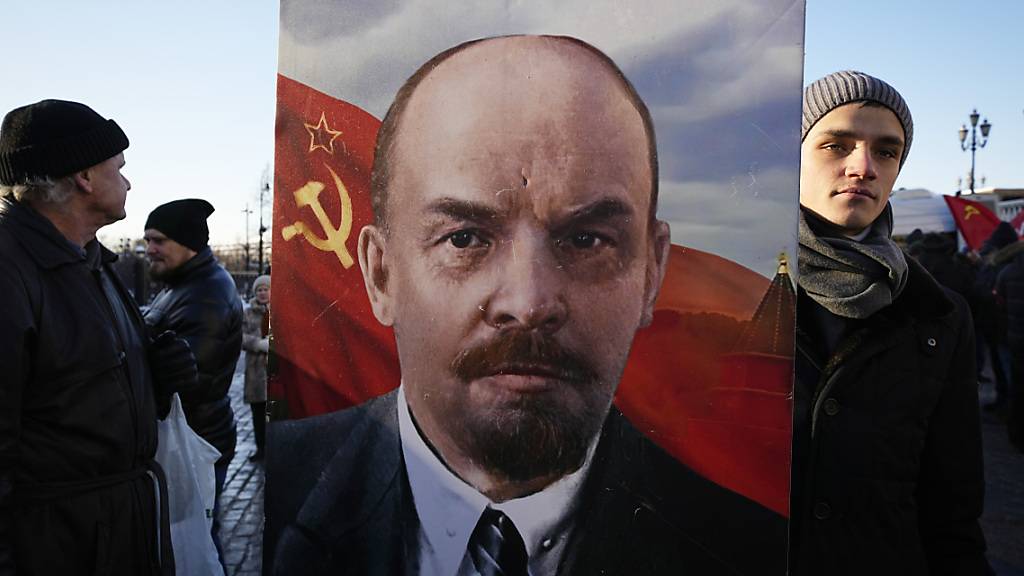 Russische kommunistische Anhänger tragen ein Porträt von Wladimir Lenin, während sie auf dem Roten Platz in Moskau Blumen am Mausoleum des Sowjetgründers Wladimir Lenin niederlegen, um dessen 100. Todestag zu feiern. Foto: Alexander Zemlianichenko/AP/dpa