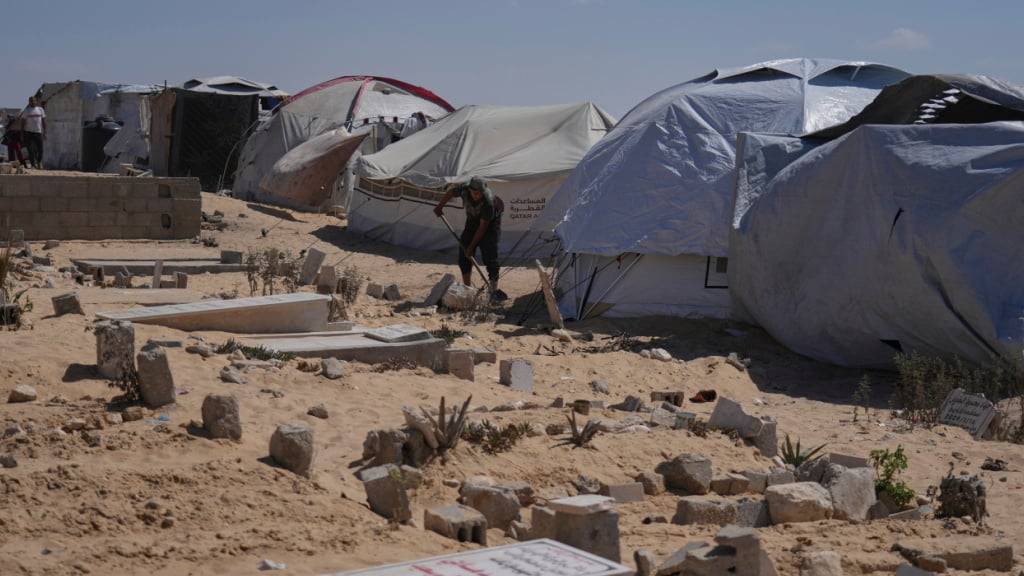 Ein Palästinenser arbeitet an einem Zelt, das er auf einem Friedhof aufgestellt hat, nachdem er aus dem nördlichen Gazastreifen vertrieben worden war. Foto: Jehad Alshrafi/AP/dpa