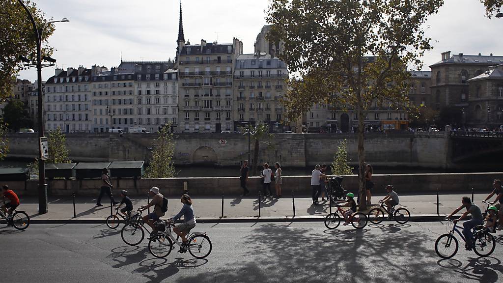 ARCHIV - Fahrradfahrer fahren auf einer autofreien Straße entlang der Seine. Foto: Thibault Camus/AP/dpa