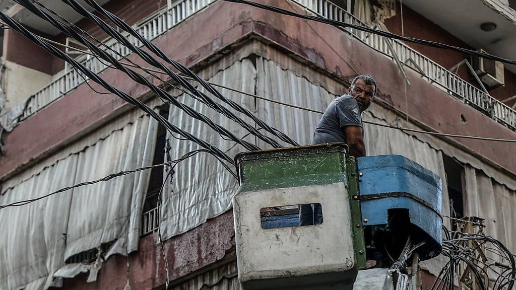 ARCHIV - Ein Elektriker entfernt Kabel von einem beschädigten Gebäude, das von einem israelischen Luftangriff in einem südlichen Vorort von Beirut getroffen wurde. Foto: Marwan Naamani/dpa