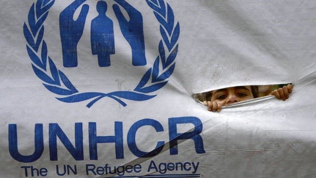 Ein Flüchtlingskind schaut durch ein UNHCR-Transparent. (Symbolbild)