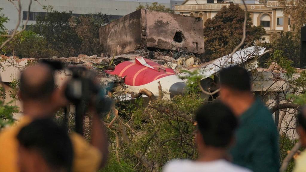 ARCHIV - Menschen betrachten die Wrackteile des abgestürzten Flugzeugs von Air India. Foto: Rafiq Maqbool/AP/dpa