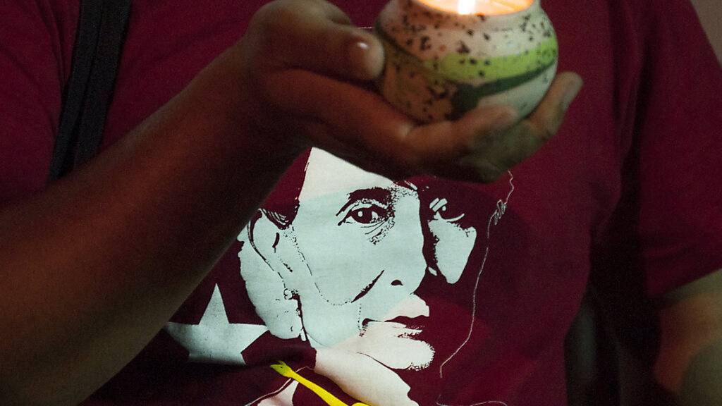 Ein Demonstrant hält während einer Demonstration eine brennende Kerze vor seinem T-Shirt mit einem Portrait von Aung San Suu Kyi, faktischer Regierungschefin von Myanmar, eine brennende Kerze. Foto: Peerapon Boonyakiat/SOPA Images via ZUMA Wire/dpa