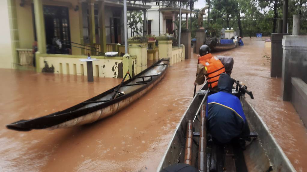 Rettungskräfte fahren mit einem Boot durch ein überflutetes Dorf. Bei anhaltendem Regen und schweren Überflutungen in Vietnam sind bis zum Montag mindestens 18 Menschen ums Leben gekommen. Foto: Ho Cau/VNA/AP/dpa
