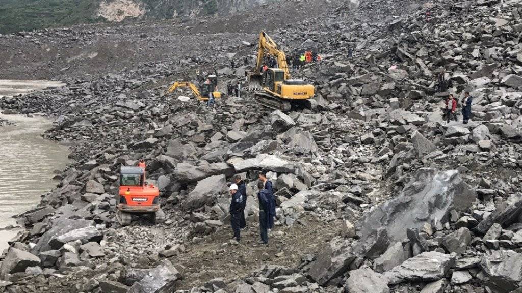 Rettungskräfte suchen mit schwerem Gerät nach Verschütteten, nachdem ein Erdrutsch in China ein ganzes Dorf under sich begraben hat.
