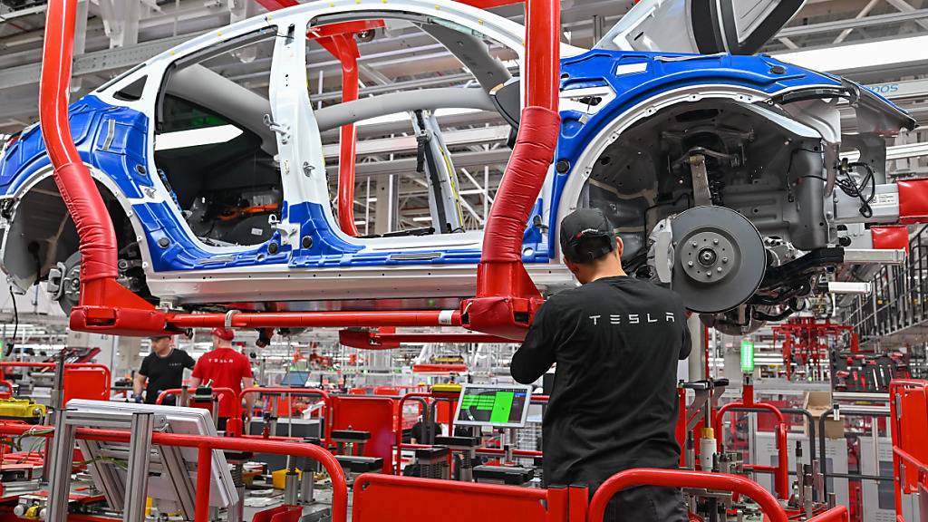 ARCHIV - Ein Mitarbeiter der Tesla Gigafactory Berlin Brandenburg arbeitet an einer Fertigungslinie eines Elektrofahrzeuges vom Typ Model Y. Foto: Patrick Pleul/dpa