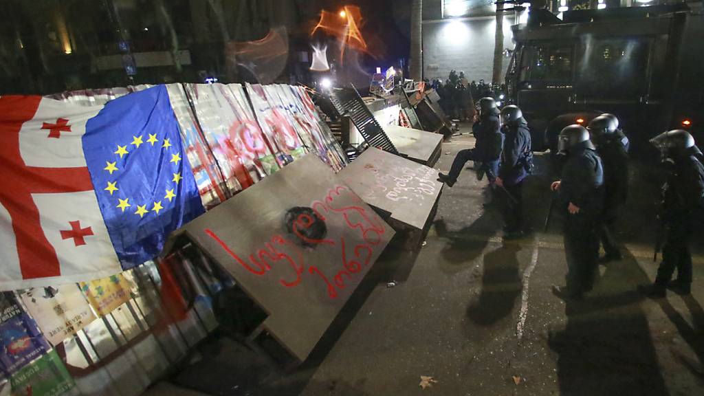 Polizisten neben einer Barrikade, die von Demonstranten während einer Kundgebung vor dem Parlamentsgebäude errichtet wurde. Foto: Zurab Tsertsvadze/AP/dpa