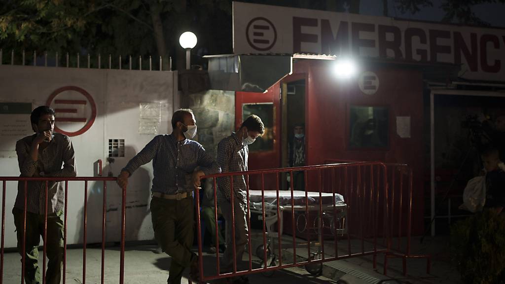 Arbeiter warten nach einer Explosion an der Eidgah-Moschee vor dem Emergency NGO Krankenhaus. Foto: Felipe Dana/AP/dpa