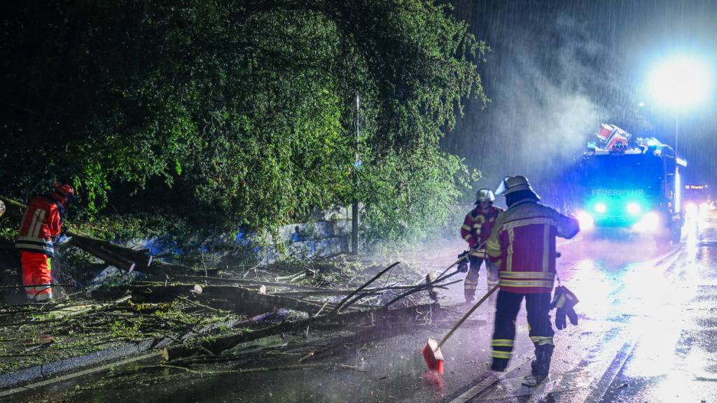 Die Feuerwehr befreit eine Straße von einem umgestürtzten Baum im Ostalbkreis. Foto: Jason Tschepljakow/dpa
