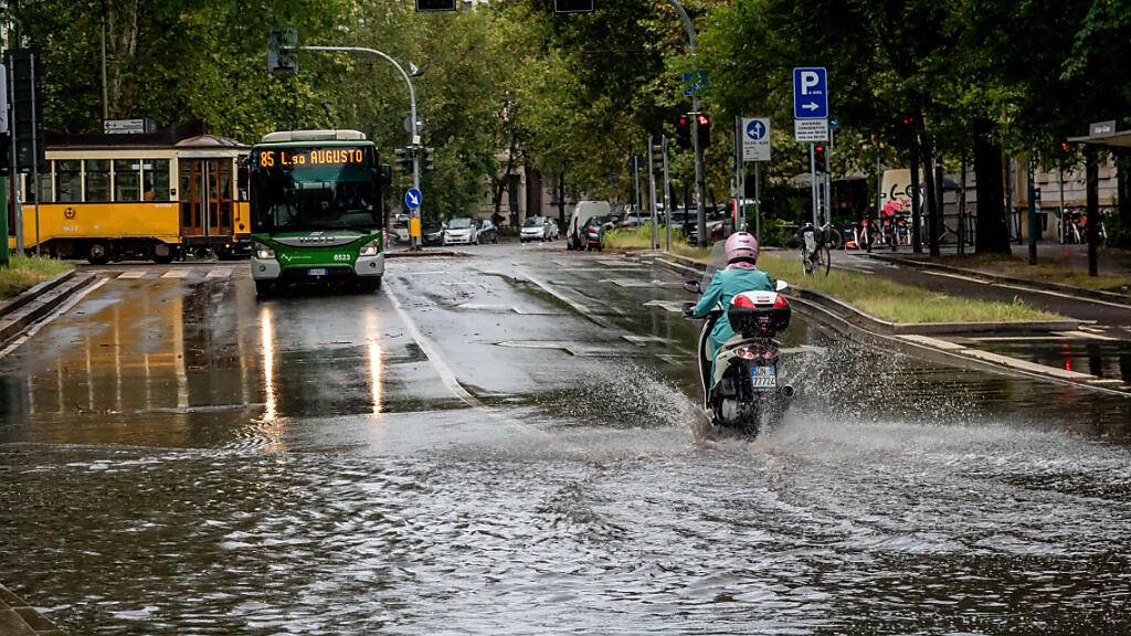 Eine Person fährt mit einem Motorroller eine überschwemmte Straße entlang. Foto: Claudio Furlan/LaPresse via ZUMA Press/dpa