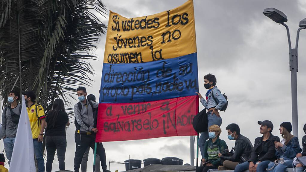 Menschen tragen eine kolumbianische Flagge, auf der geschrieben steht: «Wenn ihr jungen Leute nicht die Führung eures eigenen Landes übernehmt, wird niemand kommen, um euch zu retten, niemand». Foto: Daniel Garzon Herazo/ZUMA Wire/dpa