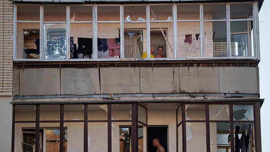 dpatopbilder - Menschen stehen auf ihren beschädigten Balkonen nach einem russischen Luftangriff auf ein Wohnviertel in Sumy. Foto: Evgeniy Maloletka/AP