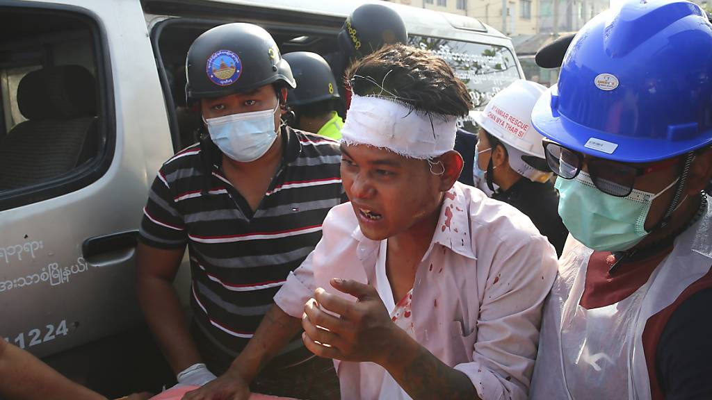 dpatopbilder - Männer begleiten einen verletzten Demonstranten. Die Polizei hatte versucht die Kundgebung, die sich gegen die Militärjunta in Myanmar richtete, aufzulösen. Foto: -/AP/dpa