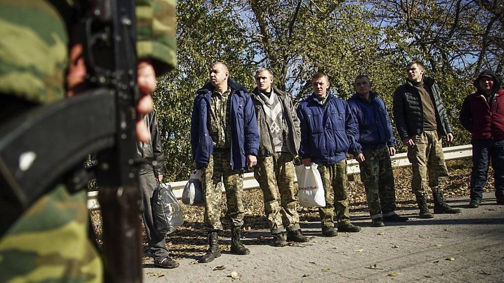 Ukrainische Soldaten warten - bewacht von prorussischen Rebellen - auf einen Gefangenenaustausch der Konfliktparteien in der Ostukraine.