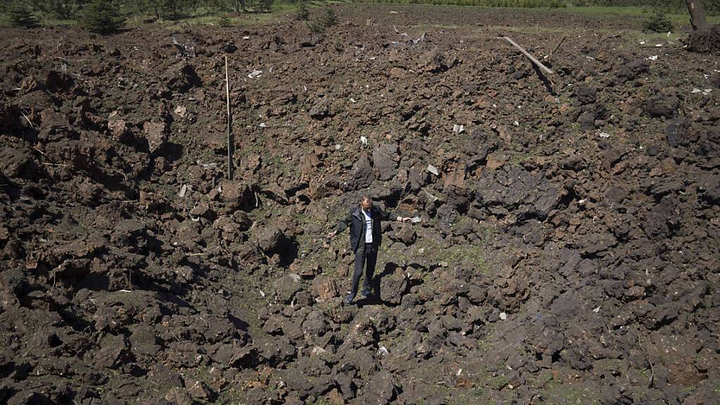 dpatopbilder - Ein Mann steht im Krater einer Explosion nach einem russischen Luftangriff in Bachmut in der Oblast Donezk in der Ostukraine. Foto: Evgeniy Maloletka/AP/dpa