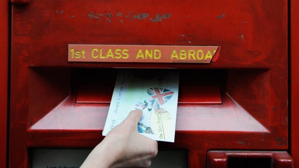 Eine Frau wirft einen Brief in einen Postkasten in London. (Archivbild)