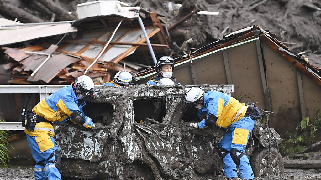 Rettungskräfte überprüfen ein beschädigtes Fahrzeug am Ort einer Schlammlawine in Atami, Präfektur Shizuoka, südwestlich von Tokio. Foto: Uncredited/Kyodo News via AP/dpa