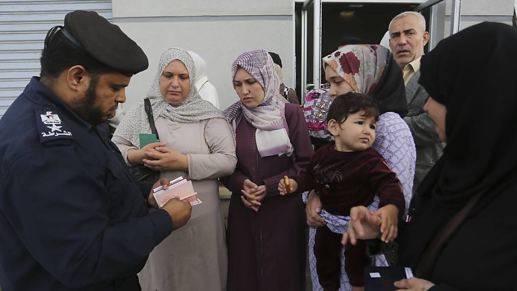 Ein Grenzbeamter prüft die Reisepässe von Palästinensern am Grenzübergang nach Ägypten. Foto: Hatem Ali/AP/dpa