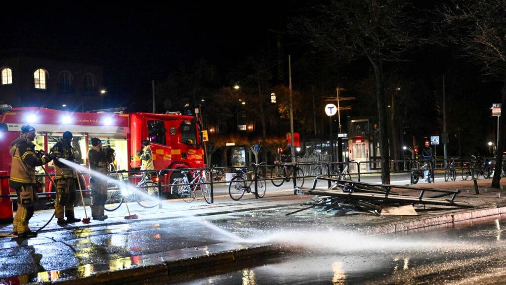 Feuerwehrleute versprühen Wasser an der Unfallstelle, nachdem ein Bus in eine Bushaltestelle gekracht ist. Foto: Henrik Montgomery/TT News Agency/AP/dpa - ACHTUNG: Nur zur redaktionellen Verwendung und nur mit vollständiger Nennung des vorstehenden Credits