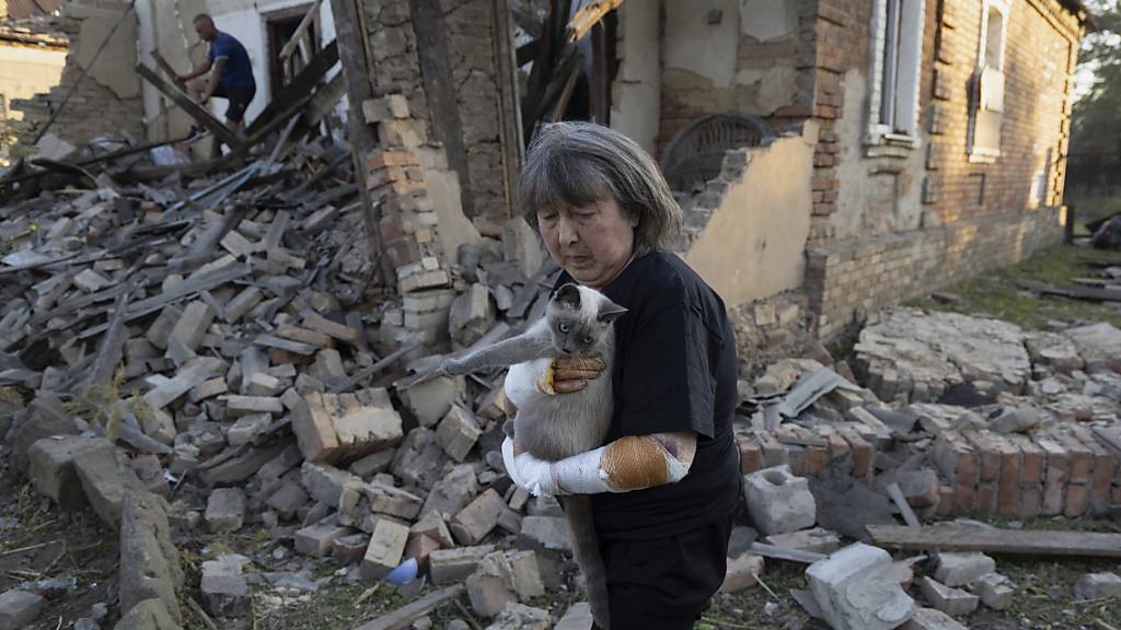 dpatopbilder - Die verletzte Ludmila Ivanchuk hält ihre Katze «Vasia» vor ihrem Haus, das durch einen Raketenangriff in Kostjantyniwka in der Region Donezk beschädigt wurde. Foto: Alex Babenko/AP/dpa