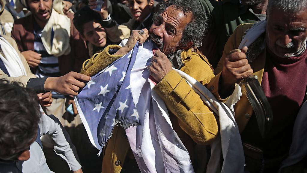 ARCHIV - Ein Anhänger der jemenitischen Huthi-Bewegung zerreißt während eines Protest vor der geschlossenen US-Botschaft eine US-Fahne, nachdem US-Außenminister Pompeo angekündigt hat, die Huthi-Rebellen als Terrororganisation einzustufen. Foto: Hani Mohammed/AP/dpa