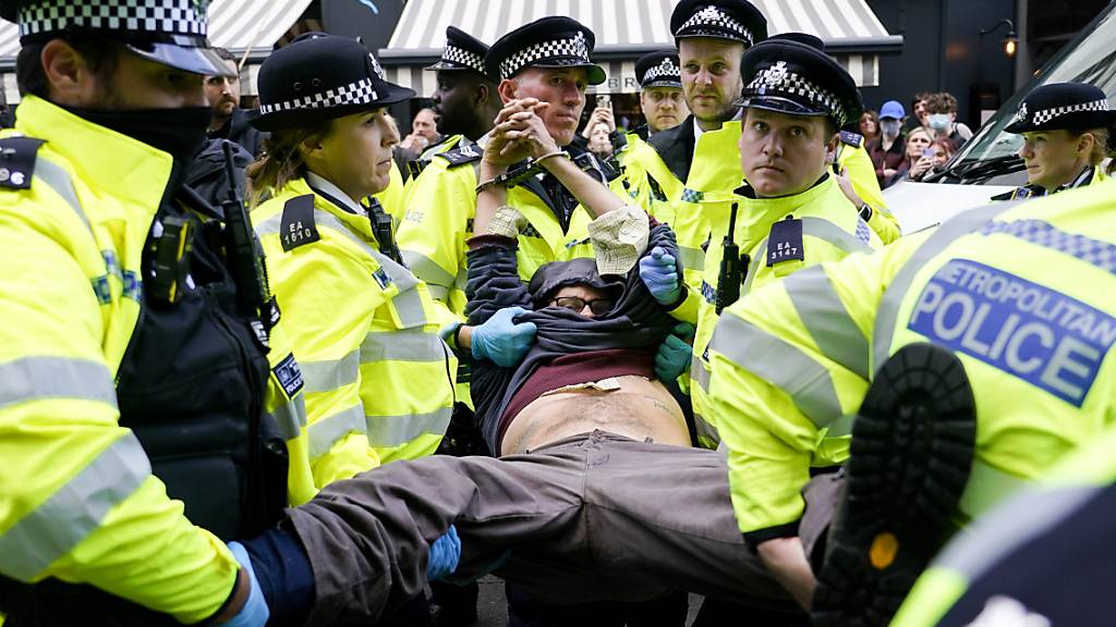 Polizisten verhaften einen Demonstranten, der sich während eines von der Umweltschutzbewegung Extinction Rebellion organisierten Protests unter einen Lieferwagen klebte. Bei der Protestaktion in London laut Mitteilung von Scotland Yard am späten Montagabend mehr als 50 Menschen festgenommen worden. Foto: Alberto Pezzali/AP/dpa
