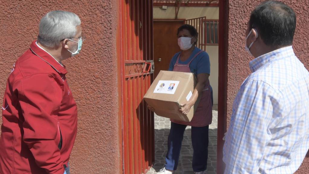 Eine Frau in Iquique bekommt ein Lebensmittelpaket. Angesichts der Corona-Krise hat die Regierung in Chile Zehntausende Lebensmittelpakete an Bedürftige verteilt. Foto: Cristian Vivero Boornes/Agencia Uno/dpa