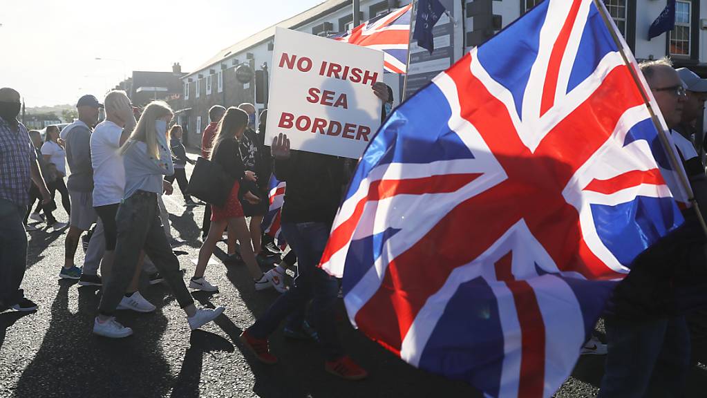 ARCHIV - Demonstranten halten britische Fahnen und ein Schild mit der Aufschrift «No Irish Sea Border» («Keine irische See-Grenze») bei einem Protest protestantischer Loyalisten gegen das sogenannte Nordirland-Protokoll. Foto: Brian Lawless/PA Wire/dpa