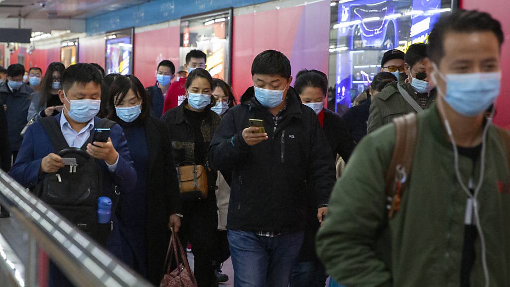 ARCHIV - Pendler schauen auf ihre Smartphones, während sie durch eine U-Bahn-Station in Peking gehen. Gut ein Jahr nach dem Ausbruch gilt das Coronavirus in China als so gut wie besiegt. Selbst in der besonders betroffenen Metropole Wuhan ist von Krise kaum noch etwas zu spüren. Foto: Mark Schiefelbein/AP/dpa